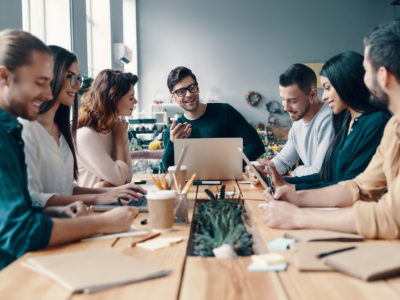 Marketing team. Group of young modern people in smart casual wear discussing something while working in the creative office